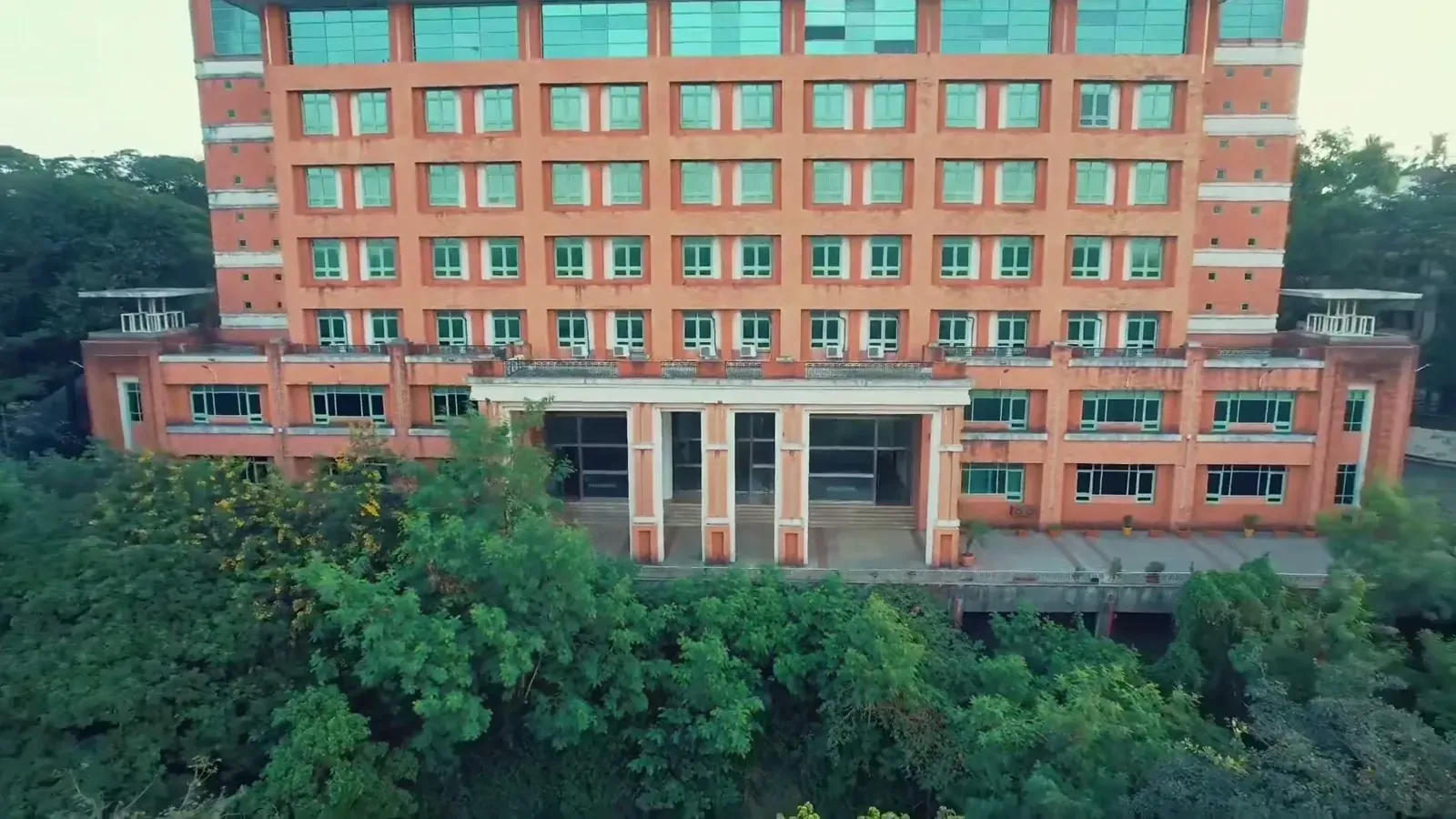 Front view of the IIM Mumbai building among the trees of the Powai campus