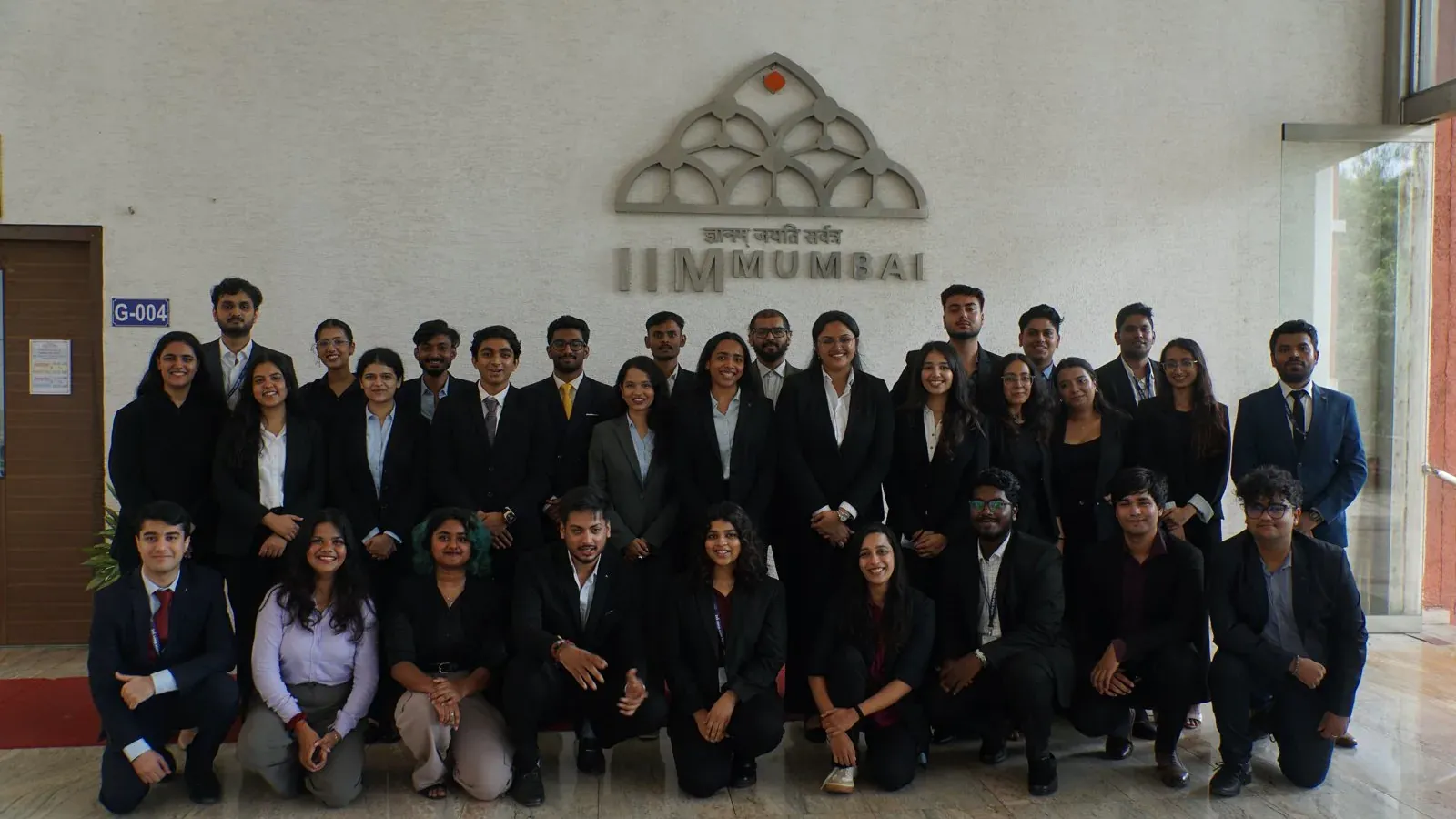 A cohort photographed in front of the IIM Mumbai emblem