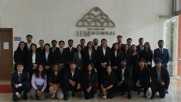 A cohort photographed in front of the IIM Mumbai emblem